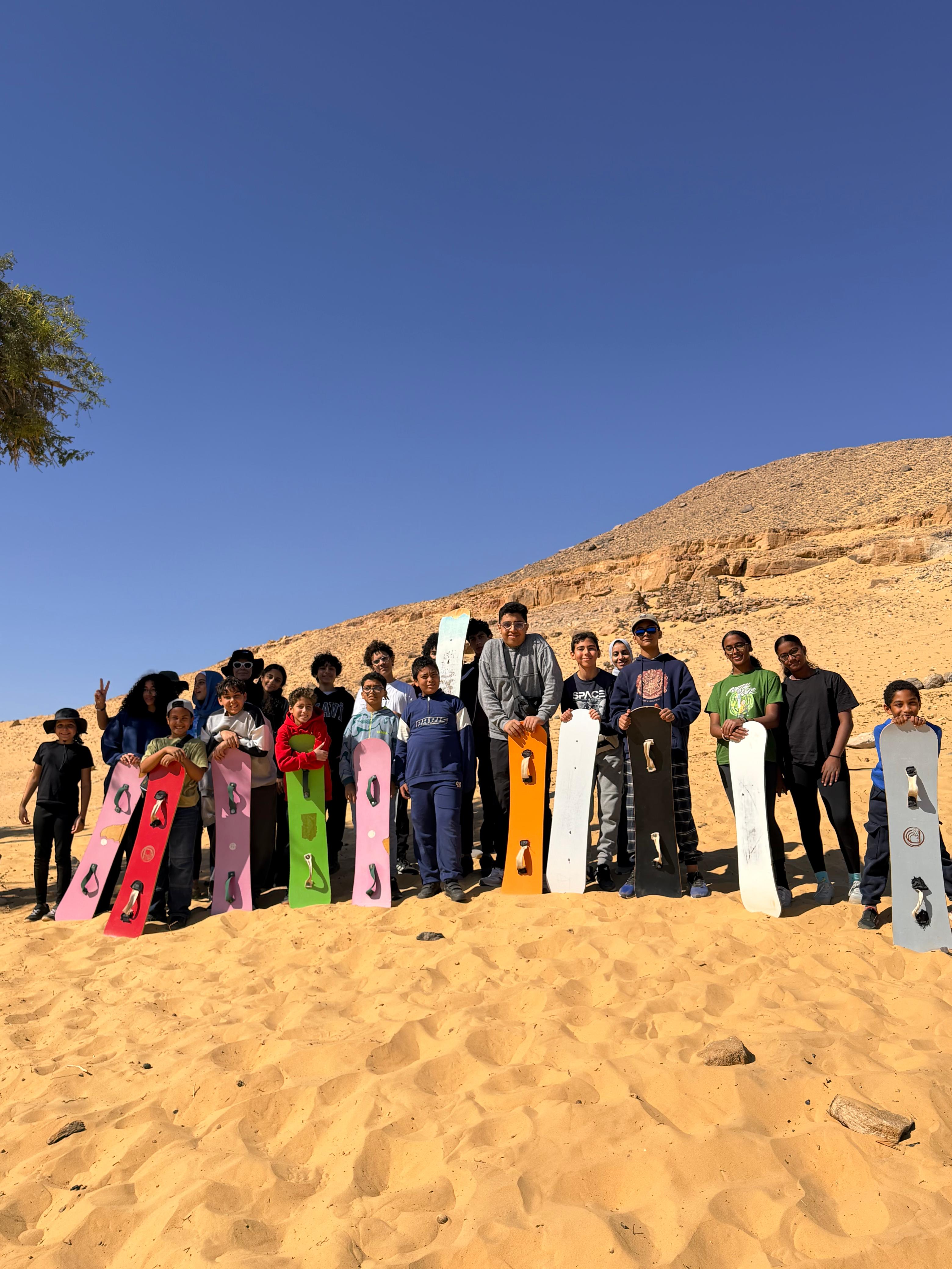Teen campers standing with sandboards in the desert